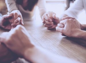 Photo of the hands of a group of people, held together in prayer