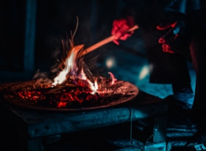 A rolled-up piece of paper is being held in the flames of a fire